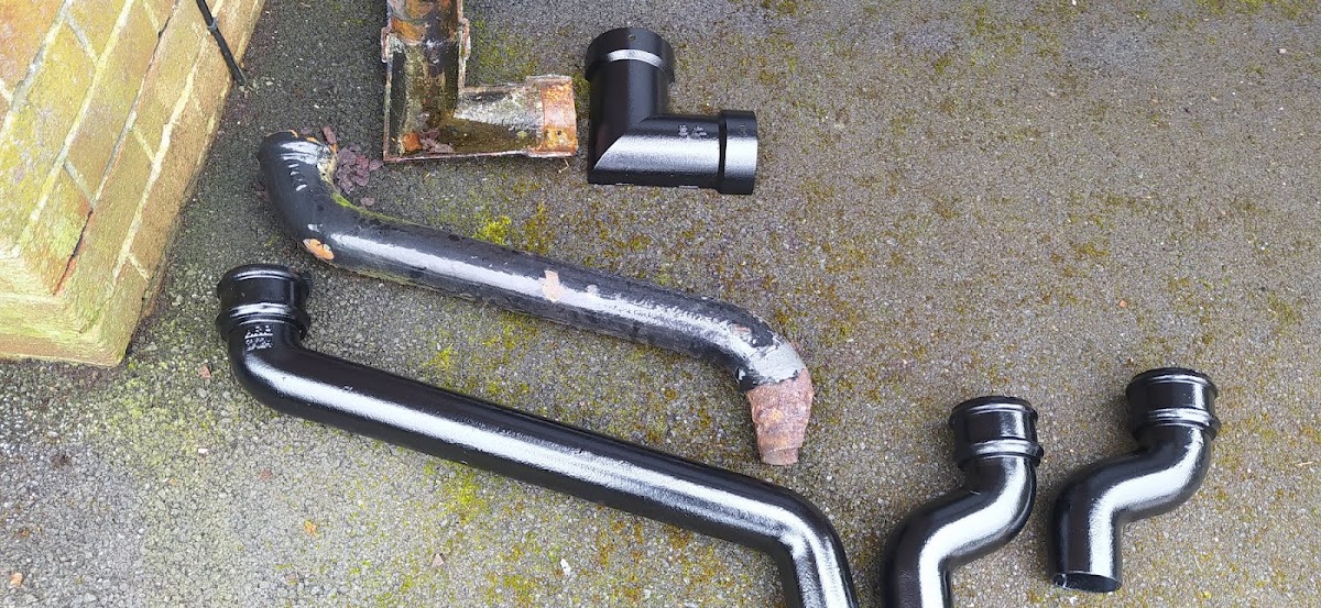 Corroded cast iron sections beside their new black replacements